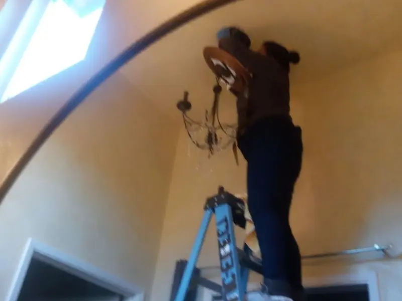 Electrician installing a chandelier in a Plymouth residence